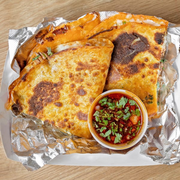 Three golden-brown Chido's Tacos birria quesadillas with a side of consome, garnished with cilantro.